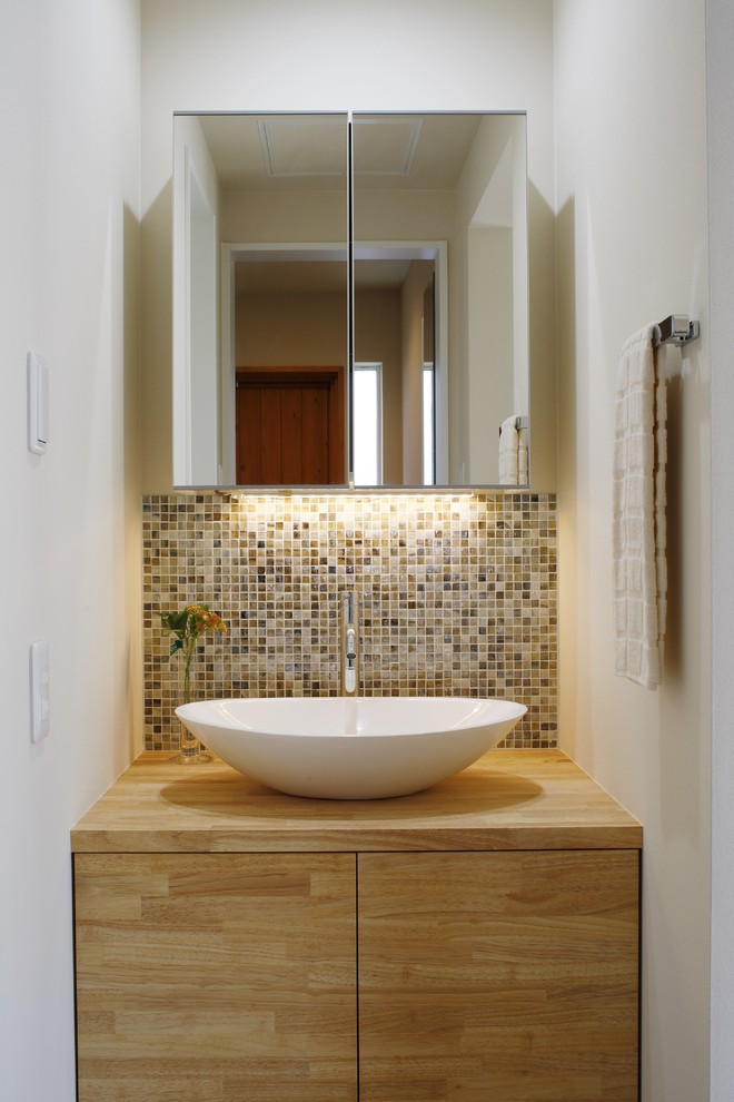 Moderne Gästetoilette mit flächenbündigen Schrankfronten, hellbraunen Holzschränken, weißer Wandfarbe, Aufsatzwaschbecken, Waschtisch aus Holz und brauner Waschtischplatte in Kyoto