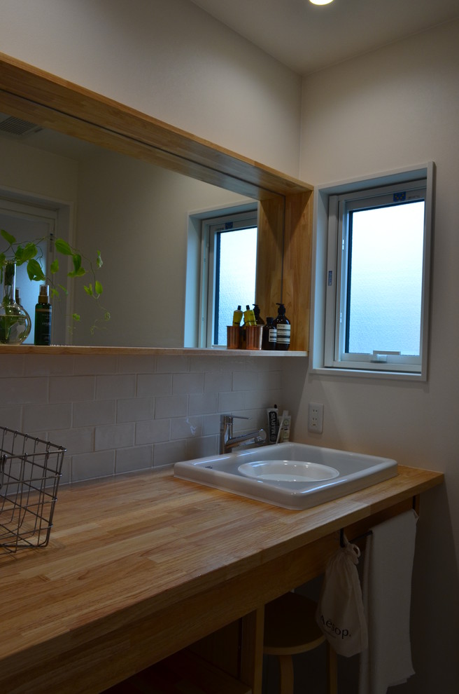 Свежая идея для дизайна: маленький туалет в скандинавском стиле с открытыми фасадами, белой плиткой, плиткой кабанчик, белыми стенами, врезной раковиной и коричневой столешницей для на участке и в саду - отличное фото интерьера
