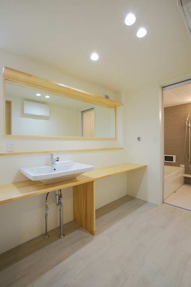 Exemple d'un WC et toilettes en bois clair avec un placard sans porte, un mur blanc, un sol en vinyl, un plan de toilette en bois et un sol gris.