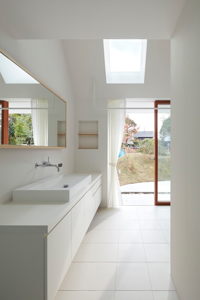 Moderne Gästetoilette mit flächenbündigen Schrankfronten, weißen Schränken, weißer Wandfarbe, Aufsatzwaschbecken, weißem Boden und weißer Waschtischplatte in Sonstige