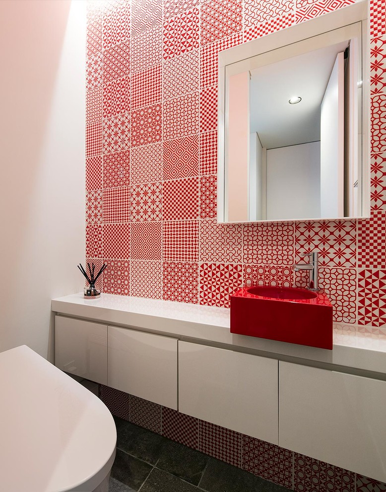 На фото: туалет в стиле модернизм с плоскими фасадами, белыми фасадами, красной плиткой, белыми стенами, настольной раковиной, серым полом и красной столешницей
