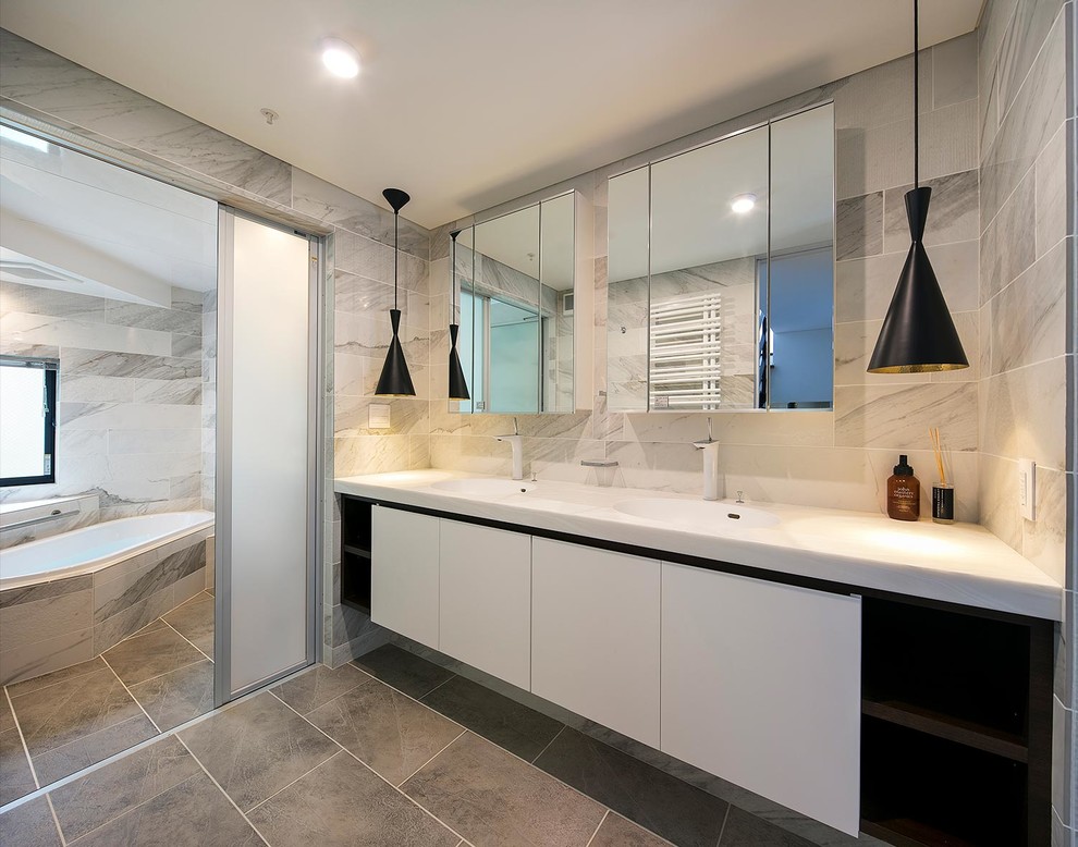 エクレクティックスタイルのおしゃれなトイレ・洗面所 (フラットパネル扉のキャビネット、茶色いキャビネット、モノトーンのタイル、グレーの壁、グレーの床、白い洗面カウンター) の写真