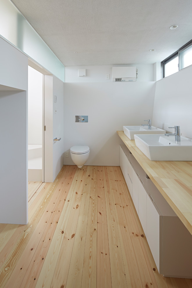 Foto de aseo minimalista con paredes blancas, suelo de madera en tonos medios, lavabo sobreencimera, encimera de madera, suelo beige y encimeras beige
