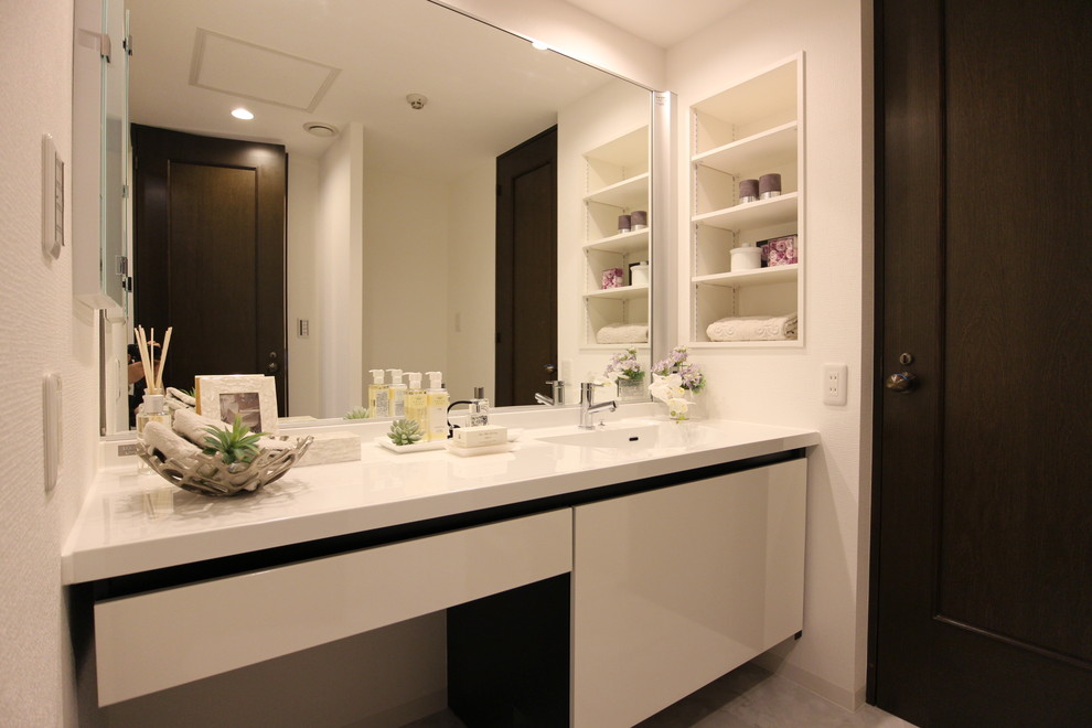 На фото: туалет в современном стиле с плоскими фасадами, белыми фасадами, белыми стенами, монолитной раковиной и серым полом с