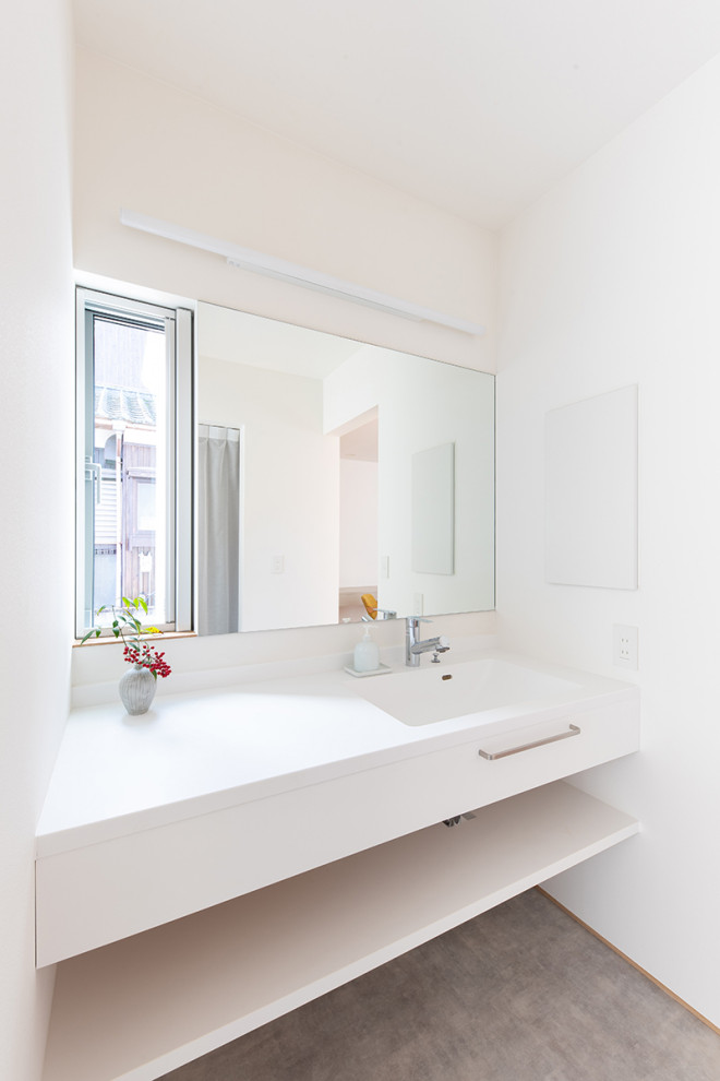 Moderne Gästetoilette mit weißen Schränken, weißer Wandfarbe, Linoleum, integriertem Waschbecken, Mineralwerkstoff-Waschtisch, grauem Boden, weißer Waschtischplatte, flächenbündigen Schrankfronten und schwebendem Waschtisch in Sonstige