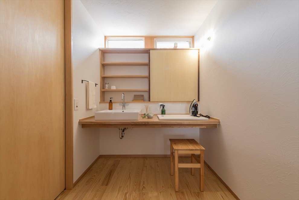 横浜にある北欧スタイルのおしゃれなトイレ・洗面所 (白い壁、無垢フローリング、ベッセル式洗面器、木製洗面台、茶色い床、ブラウンの洗面カウンター) の写真