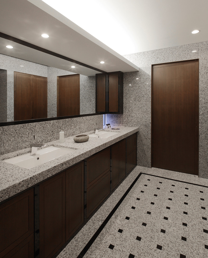 Réalisation d'un WC et toilettes minimaliste en bois foncé avec un placard à porte plane, un mur gris, un plan de toilette en granite et un sol gris.