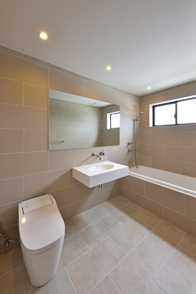 Cette image montre un WC et toilettes nordique avec un mur beige, un lavabo suspendu et un sol beige.