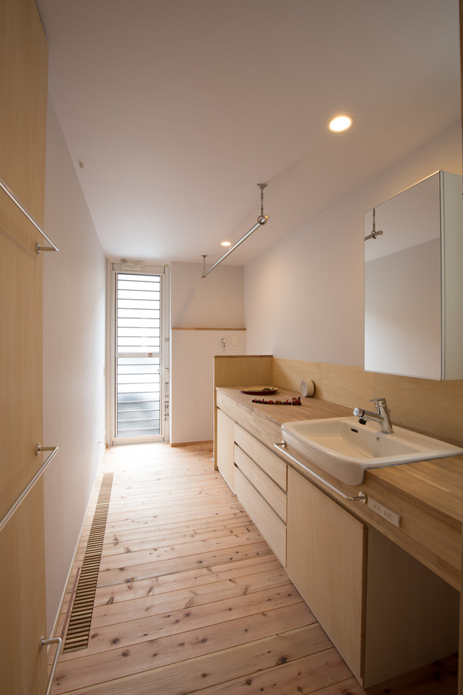 Cette photo montre un WC et toilettes scandinave en bois clair avec un placard à porte plane, un mur blanc, parquet clair, un plan de toilette en bois, un sol beige et un plan de toilette beige.