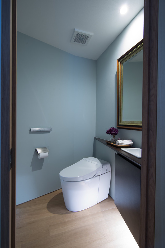 Inspiration pour un WC et toilettes vintage de taille moyenne avec un mur bleu, parquet clair, un sol beige, un lavabo posé et un plan de toilette en bois.