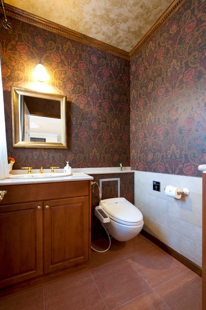 Aménagement d'un WC suspendu victorien en bois brun avec un placard avec porte à panneau surélevé, un mur multicolore, tomettes au sol, un lavabo posé et un sol marron.