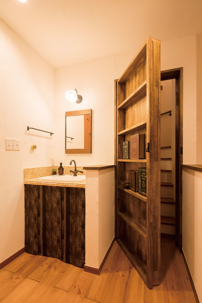 Idée de décoration pour un WC et toilettes asiatique en bois foncé avec un mur blanc, un sol en bois brun, un lavabo posé et un sol marron.