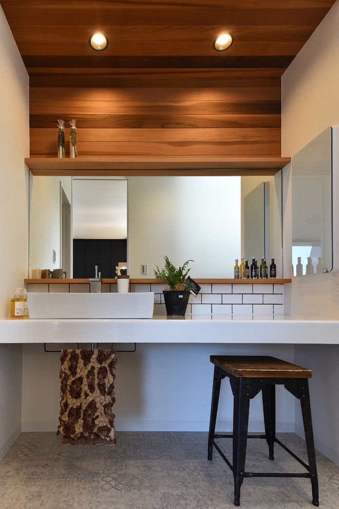 Photo of a world-inspired cloakroom in Other with white walls, a vessel sink and grey floors.