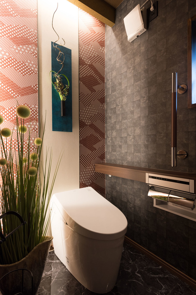 На фото: туалет в современном стиле с унитазом-моноблоком, серыми стенами, черной плиткой и разноцветным полом