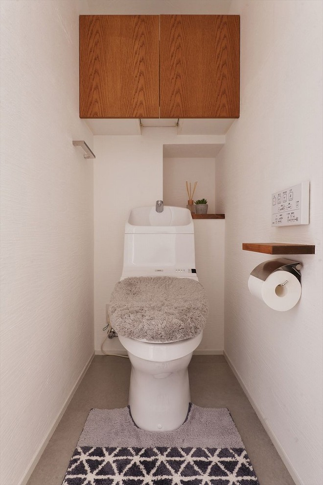 Idées déco pour un WC et toilettes méditerranéen avec un mur blanc, sol en béton ciré et un sol gris.