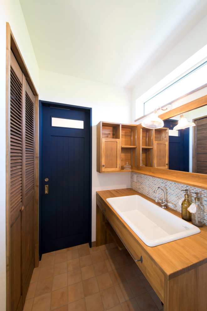 Immagine di un bagno di servizio etnico con piastrelle beige, pareti bianche, lavabo rettangolare, pavimento in terracotta, ante in legno scuro e ante lisce