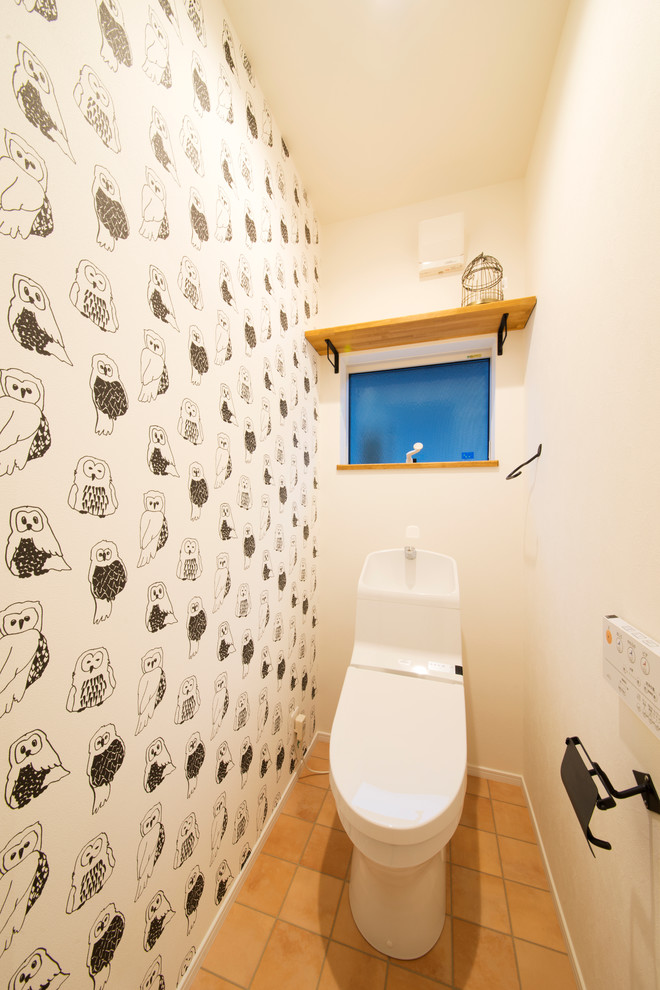 Réalisation d'un WC et toilettes champêtre avec WC à poser, un mur blanc et tomettes au sol.