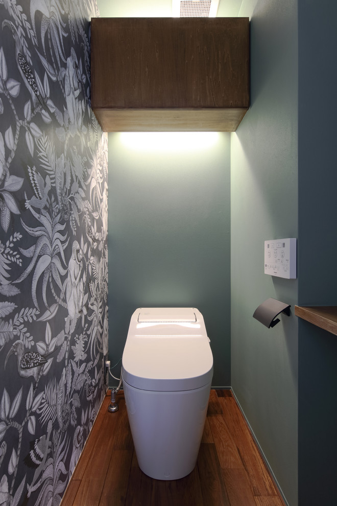 Diseño de aseo minimalista con paredes multicolor, suelo de madera en tonos medios y suelo marrón