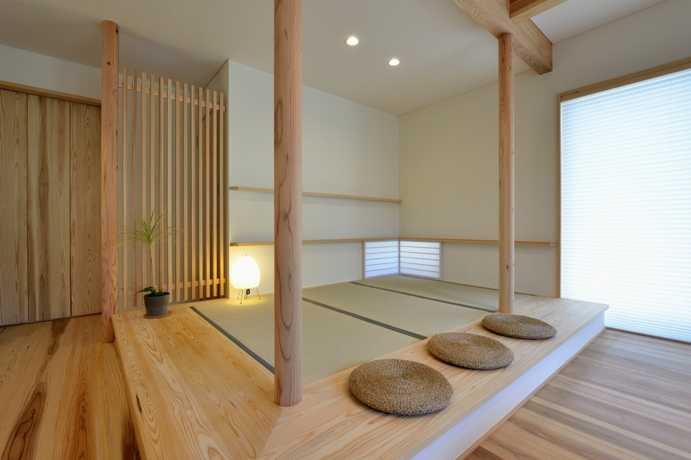 Cette image montre une salle de séjour asiatique ouverte avec un mur blanc, un sol de tatami, aucun téléviseur et un sol beige.