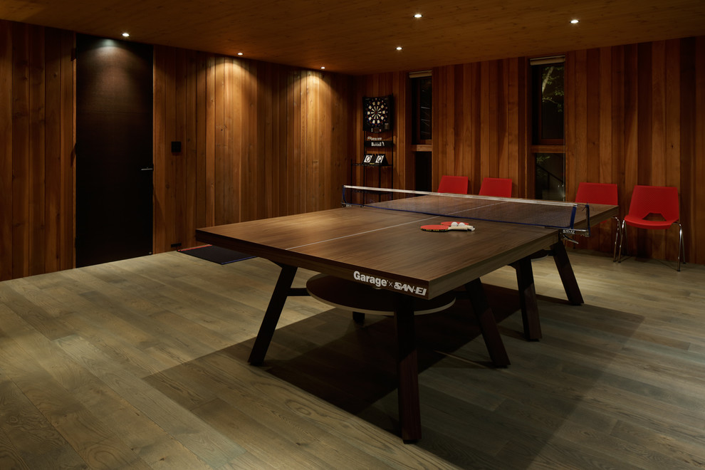 Modelo de sala de juegos en casa moderna con paredes marrones y suelo de madera oscura