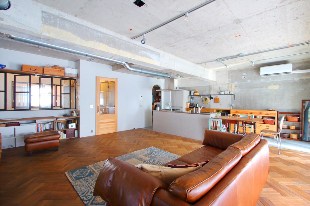 Immagine di un soggiorno industriale aperto con pareti grigie, pavimento in legno massello medio e pavimento marrone