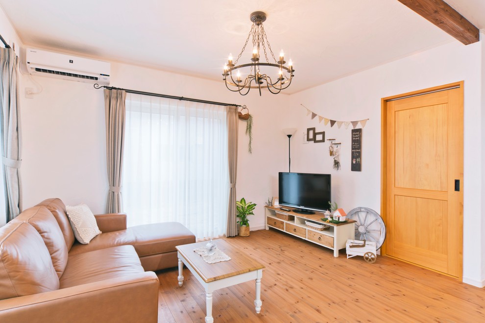 Immagine di un soggiorno mediterraneo con pareti bianche, pavimento in legno massello medio, TV autoportante e pavimento marrone