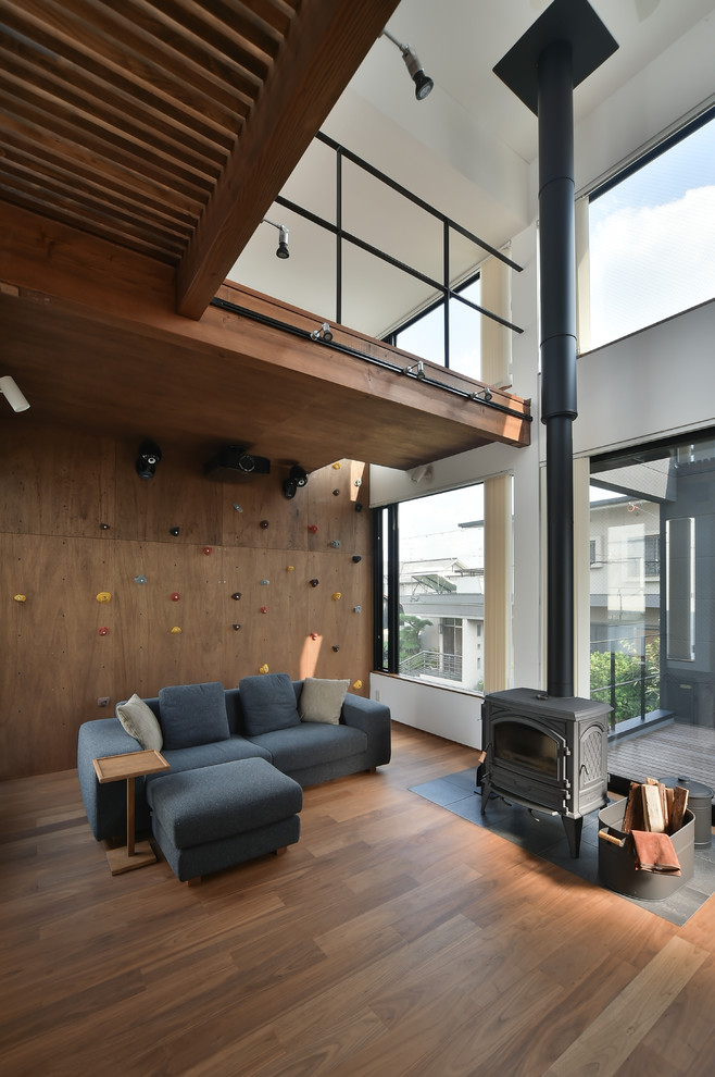 Idée de décoration pour une salle de séjour asiatique ouverte avec un poêle à bois, un manteau de cheminée en carrelage, un mur marron, un sol en bois brun et un sol marron.