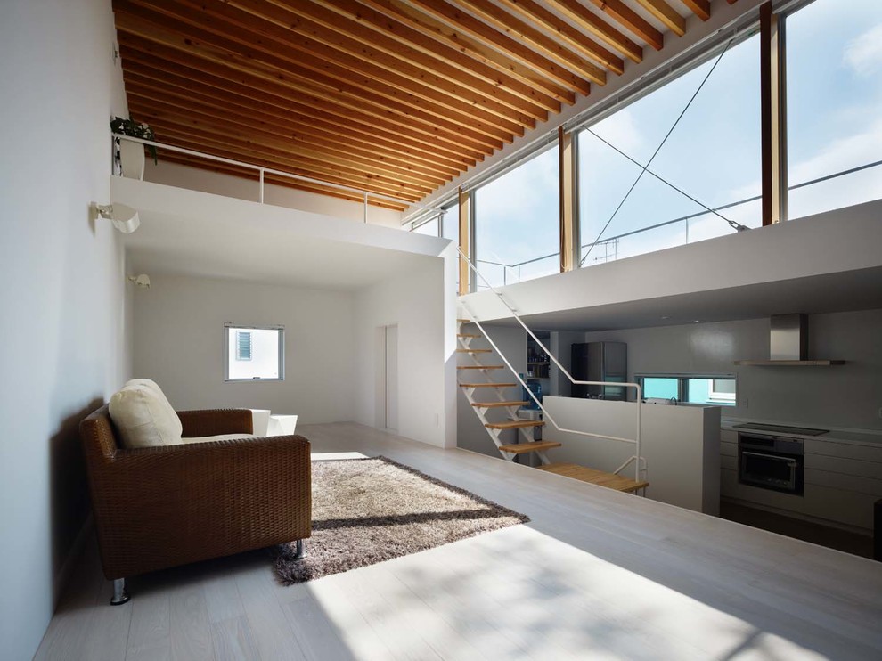 Modelo de sala de estar abierta contemporánea grande con paredes blancas, suelo de madera pintada, suelo gris y televisor colgado en la pared