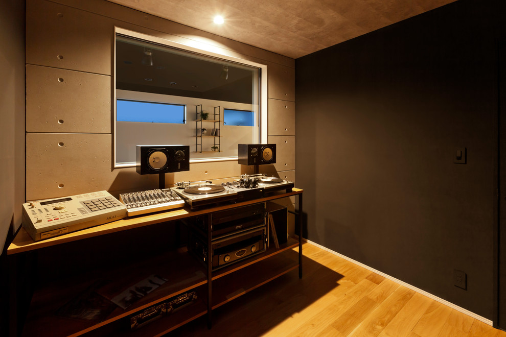 Bild på ett funkis allrum, med ett musikrum, svarta väggar, mellanmörkt trägolv och brunt golv