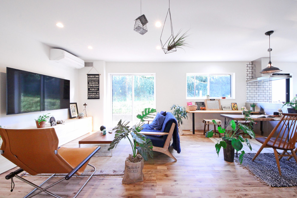 Modelo de sala de estar industrial con paredes blancas, suelo de madera en tonos medios, televisor colgado en la pared y suelo marrón