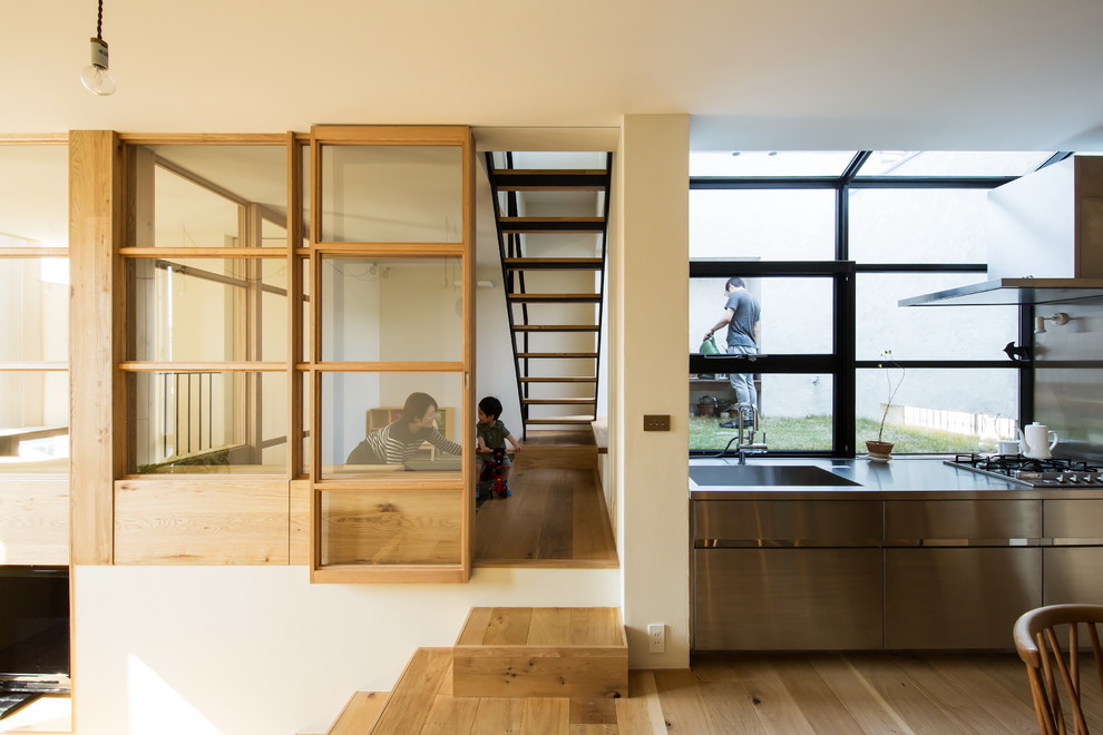 Cette photo montre une salle de séjour tendance ouverte avec un mur blanc et un sol en bois brun.