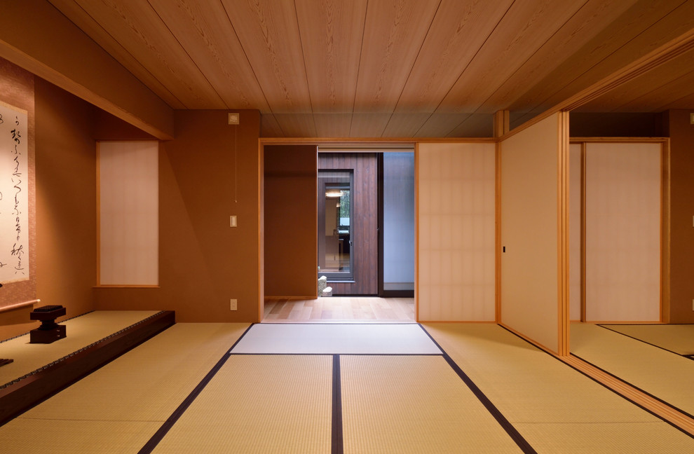 Cette image montre une salle de séjour asiatique fermée avec un mur marron, un sol de tatami et un sol vert.