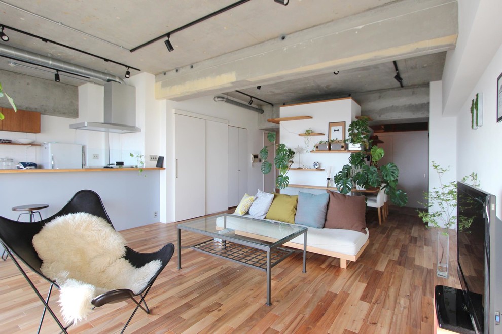 Foto di un soggiorno industriale aperto con pareti bianche, pavimento in legno massello medio, nessun camino e TV autoportante