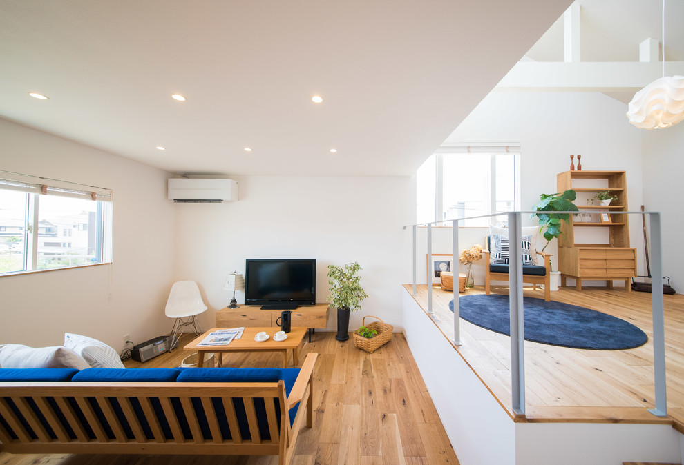 Inspiration pour une salle de séjour nordique ouverte avec un mur blanc, un sol en bois brun, un téléviseur indépendant et un sol marron.