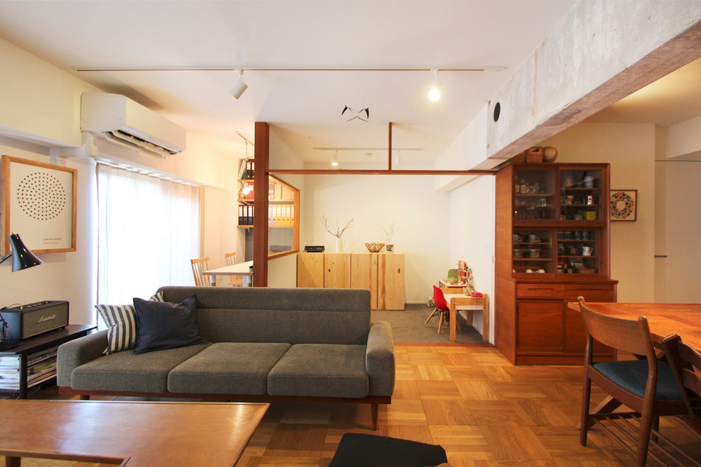 Exempel på ett asiatiskt allrum med öppen planlösning, med vita väggar, mellanmörkt trägolv, en fristående TV och brunt golv