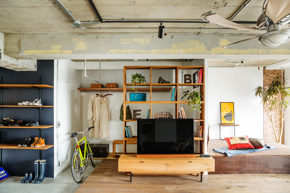 Cette photo montre une salle de séjour industrielle avec un mur blanc, un sol en bois brun, aucune cheminée et un téléviseur indépendant.