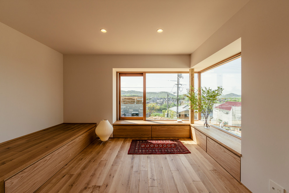 Family room - zen medium tone wood floor and brown floor family room idea in Other with beige walls