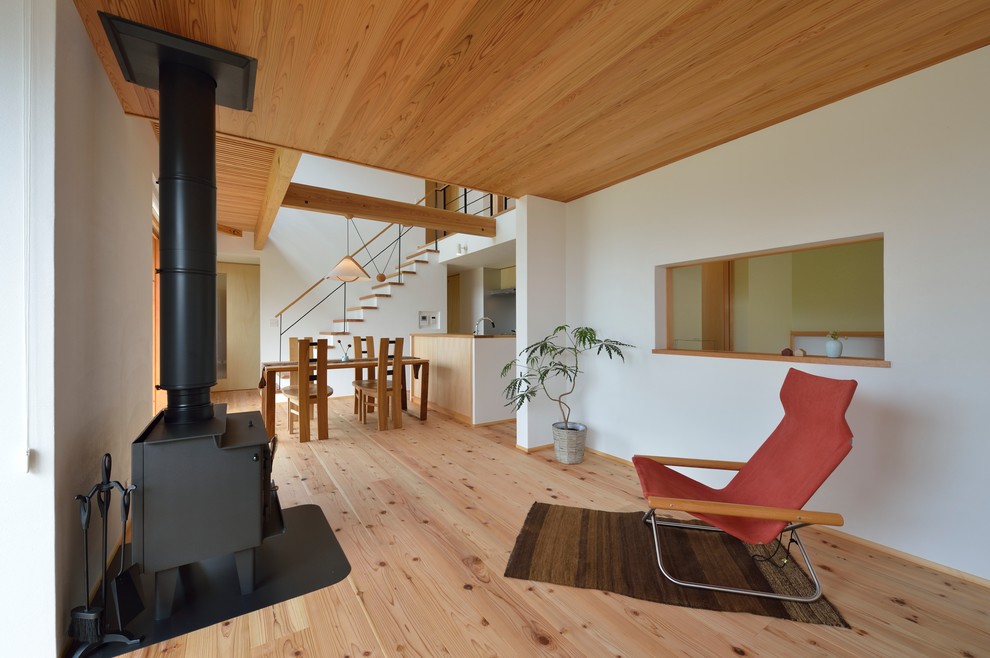 Modelo de sala de estar abierta de estilo zen con paredes blancas, suelo de madera clara y suelo marrón
