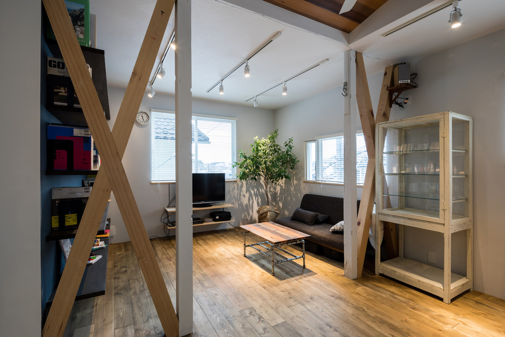 Foto di un soggiorno industriale aperto con pareti bianche, pavimento in legno massello medio, TV autoportante e pavimento marrone