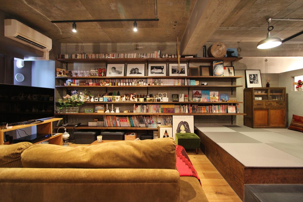 Réalisation d'une salle de séjour urbaine avec une bibliothèque ou un coin lecture, un sol en bois brun et un sol marron.