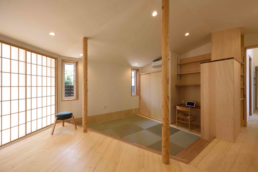Immagine di un soggiorno stile rurale di medie dimensioni e aperto con libreria, pareti bianche, pavimento in tatami, TV a parete e pavimento verde