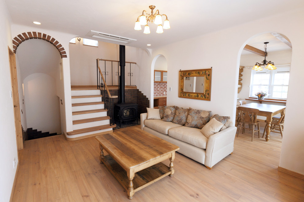На фото: гостиная комната в скандинавском стиле с белыми стенами, светлым паркетным полом и коричневым полом