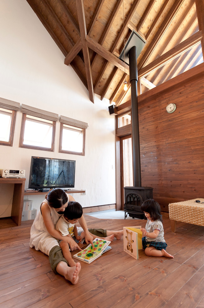 Réalisation d'une salle de séjour asiatique ouverte avec un mur blanc, parquet foncé, un poêle à bois, un manteau de cheminée en béton et un téléviseur indépendant.