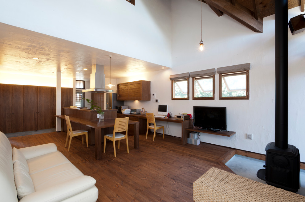 Diseño de sala de estar abierta asiática con paredes blancas, suelo de madera oscura, estufa de leña, marco de chimenea de hormigón y televisor independiente