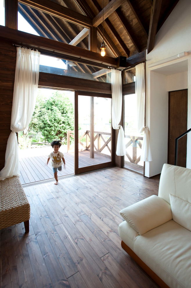 Diseño de sala de estar abierta asiática con paredes blancas y suelo de madera oscura
