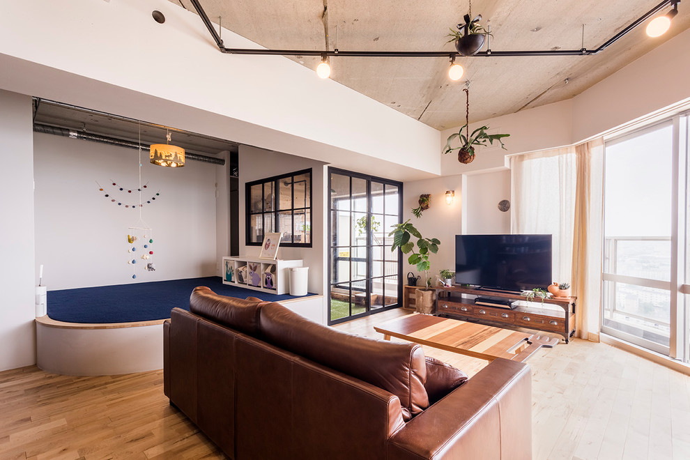 Foto de sala de estar abierta industrial con paredes blancas, suelo de madera clara, televisor independiente y suelo marrón