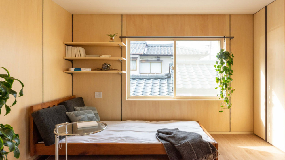 Modelo de sala de estar abierta asiática con paredes beige, suelo de madera en tonos medios y televisor independiente