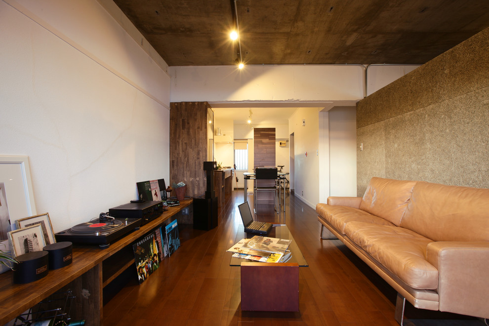 Идея дизайна: гостиная комната в стиле лофт с белыми стенами, темным паркетным полом и коричневым полом