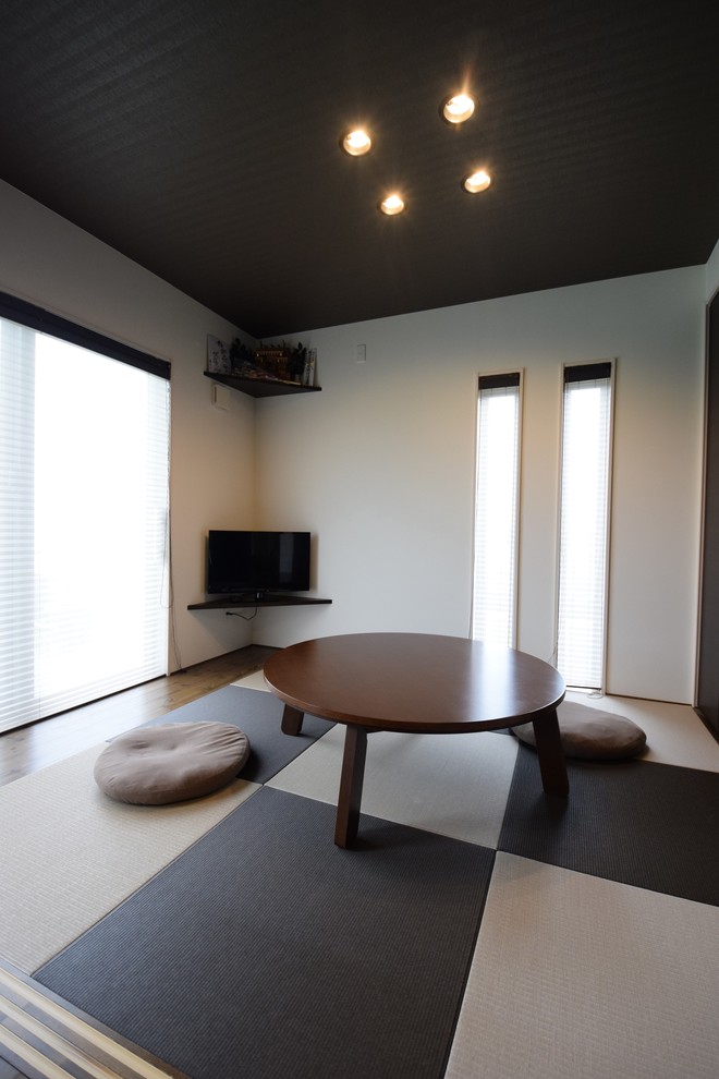 На фото: гостиная комната в восточном стиле с белыми стенами, татами, отдельно стоящим телевизором и разноцветным полом с