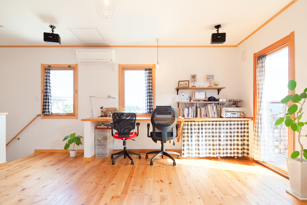 Imagen de despacho nórdico grande con biblioteca, paredes blancas, suelo de madera en tonos medios y suelo marrón